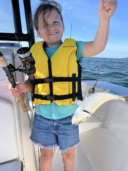 A young angler with her first fish of the day on the line