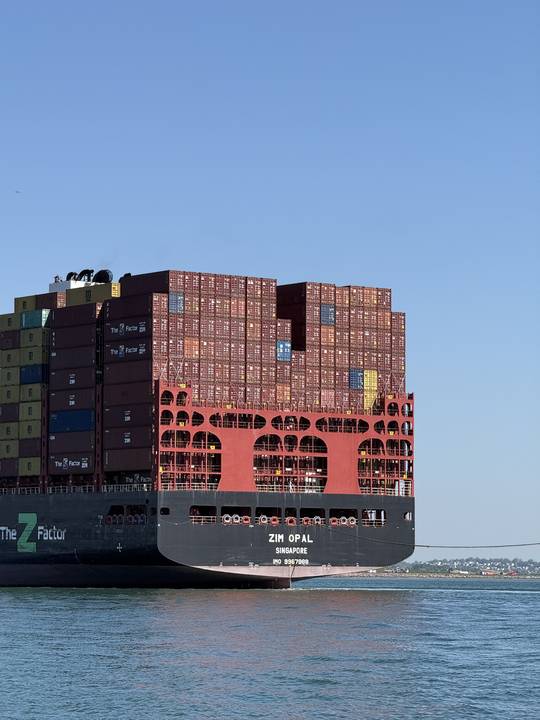 The stern of a container ship stacked high, inbound to Conley