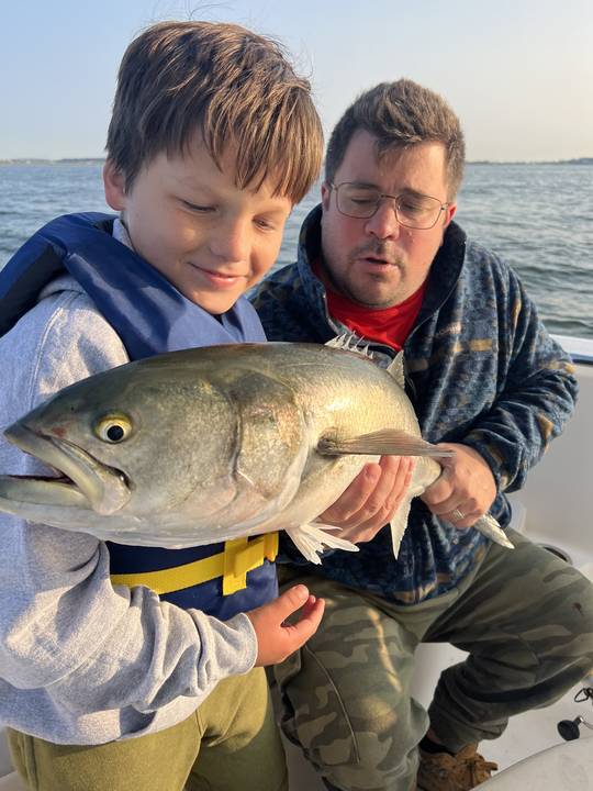 A boy and his dad looking at a bluefish in low evening light