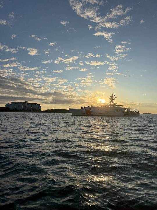 A Coast Guard cutter on station as the sun goes down