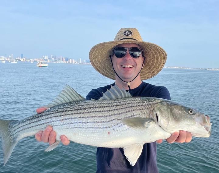 Striper held up in a straw hat on a flat calm day