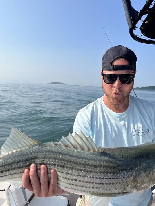 Striped bass held up on a hazy summer morning