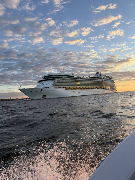 A cruise ship outbound past the islands at sunset