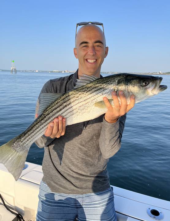 Striper held up beside a green channel marker