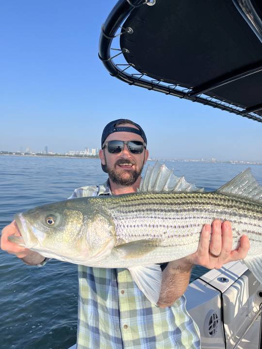 Striped bass held under the T-top on a bright day
