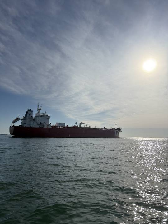 A tanker in silhouette with the sun off the water