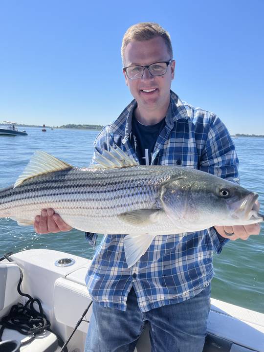 Striped bass held up on a bluebird day in the harbor